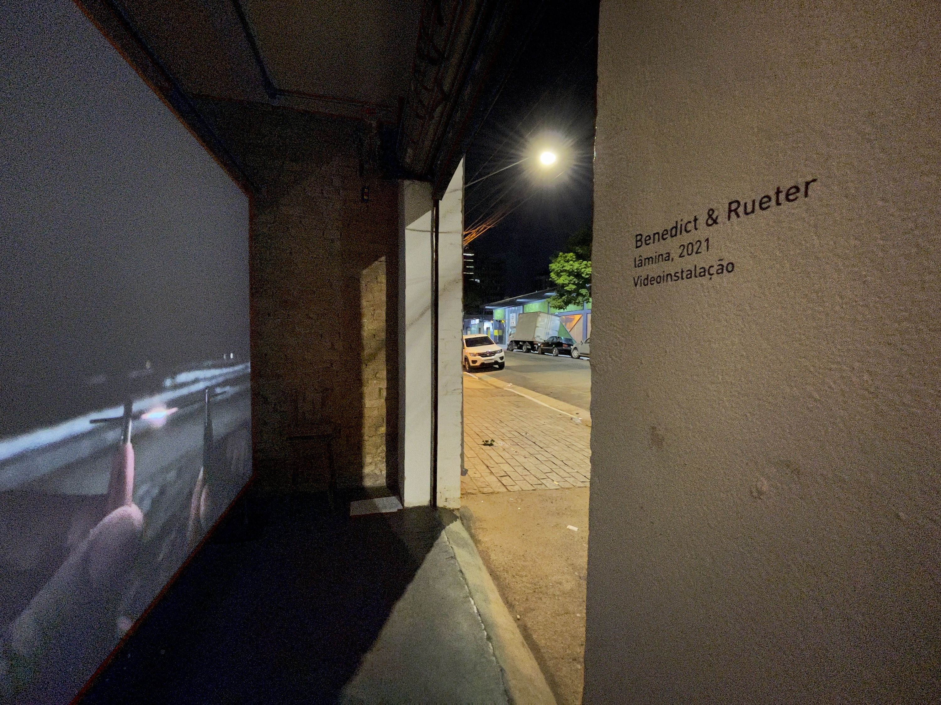 Marissa Lee Benedict and David Rueter, lâmina, 2021, Single-channel video installation, 2:00 TRT, Commissioned for the São Paulo project space um trabalho um texto (one work one text), lâmina is a one-night video work – a singular gesture – exhibited in parallel with a text by curator João Paulo Quintella. Documenting two hands, tentatively, awkwardly, bringing two pieces of 0.7 mm pencil lead (graphite) close enough to spark an electric carbon arc — an early form of spark lighting used for projecting films — before burning out, the work tightly loops together the history of moving image and its means of production.
This tight loop loosens over the course of the evening with a pile-up of strange and unexpected encounters: between the congenial atmosphere of the project space and the passing audience on the street; between the humming fan of a digital projector and the roar of traffic; between the loud squealing kisses of tiny graphite pencil lead rods, powered by a motorcycle battery, burning into light; and between the projected image of a beach at the mouth of a major colonial shipping channel, and the threshold of a garage door.
The exhibition contract for lâmina dictates that this version of the video (not including documentation of the video in situ) will only be publicly shown once (from sunset 18:04:00 to midnight on 26 September 2020 R. Rocha, 386 - Bela Vista, São Paulo, 013300-000, Brazil).

